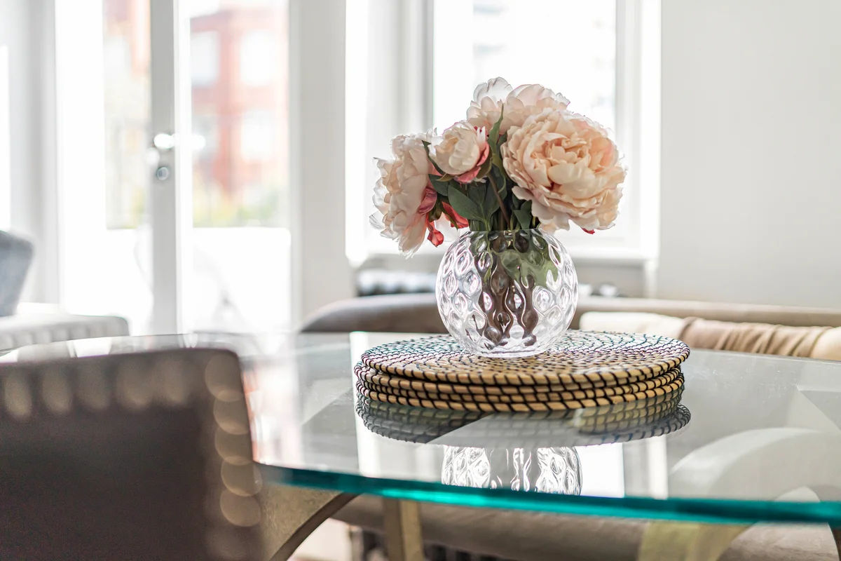 Decorative vase with fresh flowers on a glass table at Casa Cribs adding elegance.