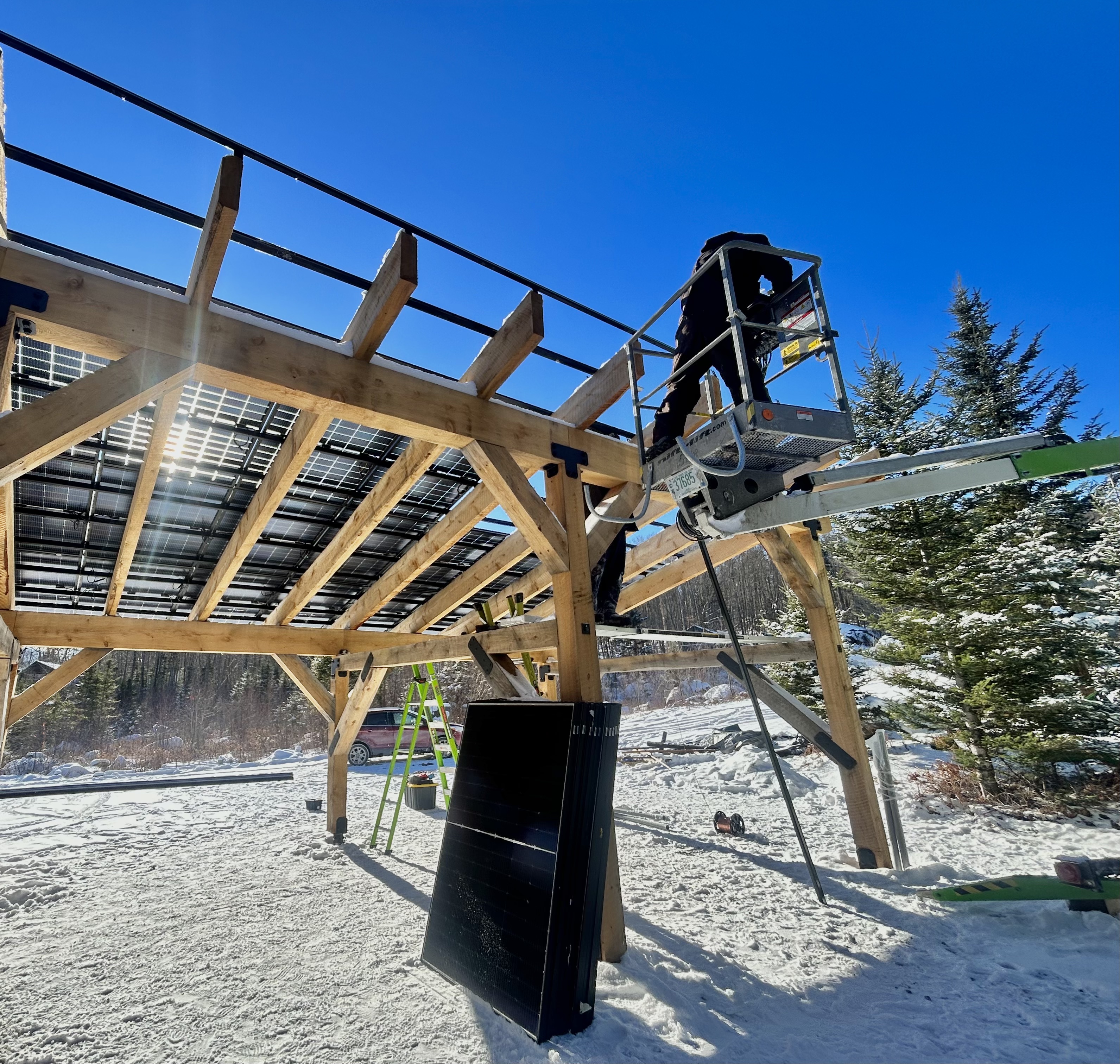Timber solar carport structure with panels installed at a snowy Vermont property