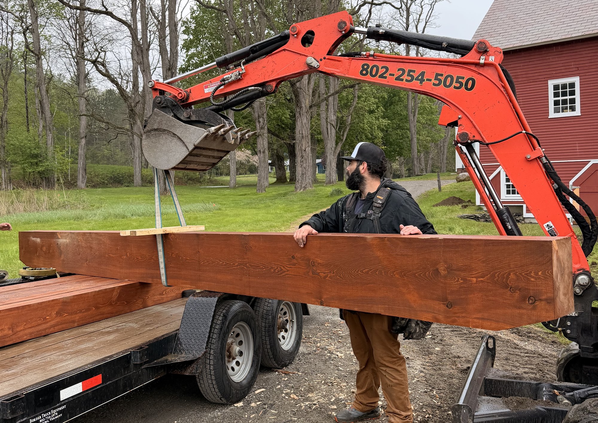 A Kingdom Sun crew member loading pre-cut, stained timber beams for delivery to a build site