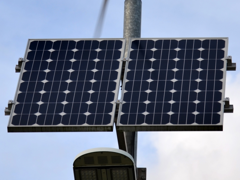 Two monocrystalline solar panels mounted on a pole against a blue sky