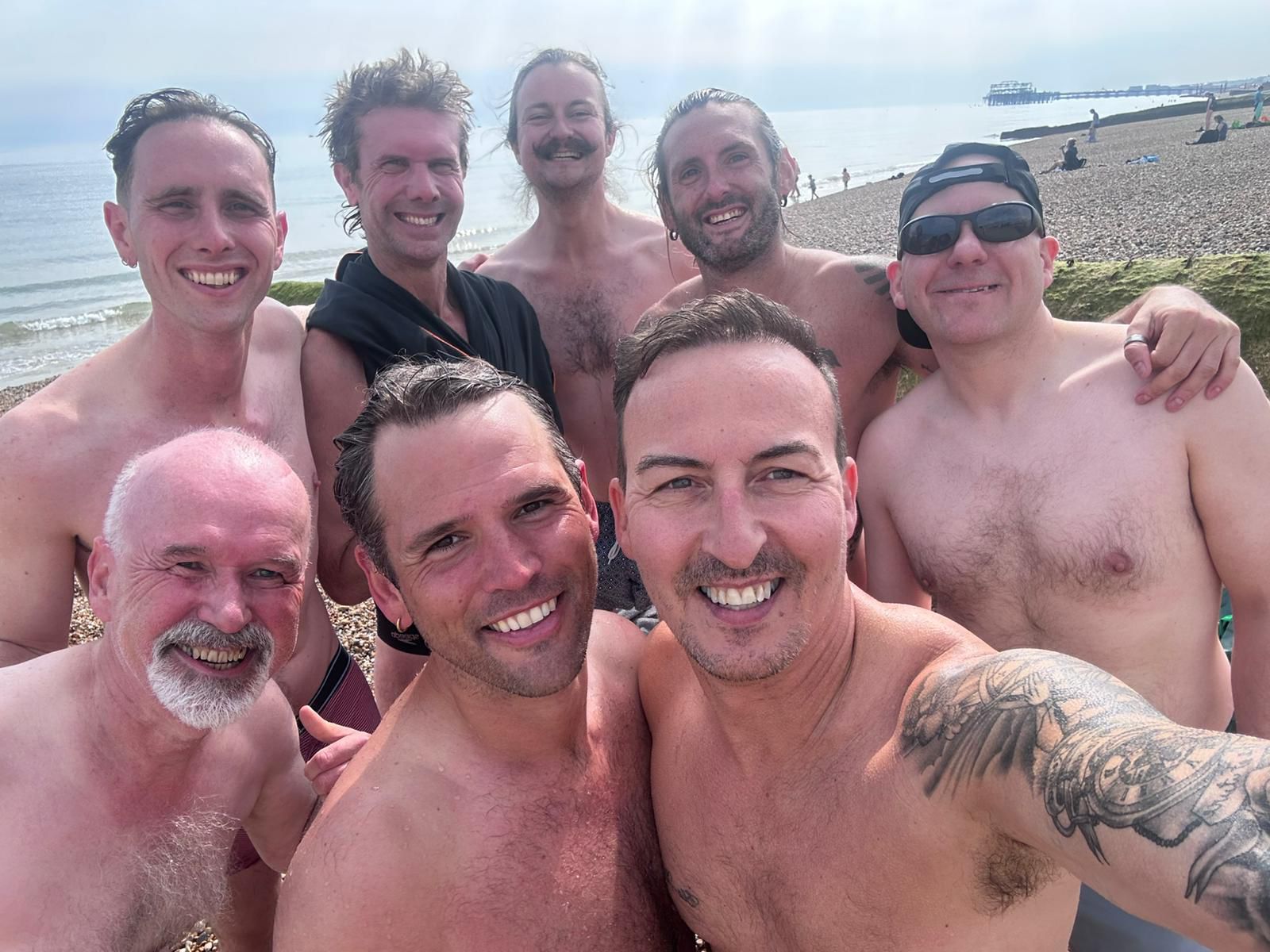 Eight Tonic members smiling taking a selfie on Brighton beach.