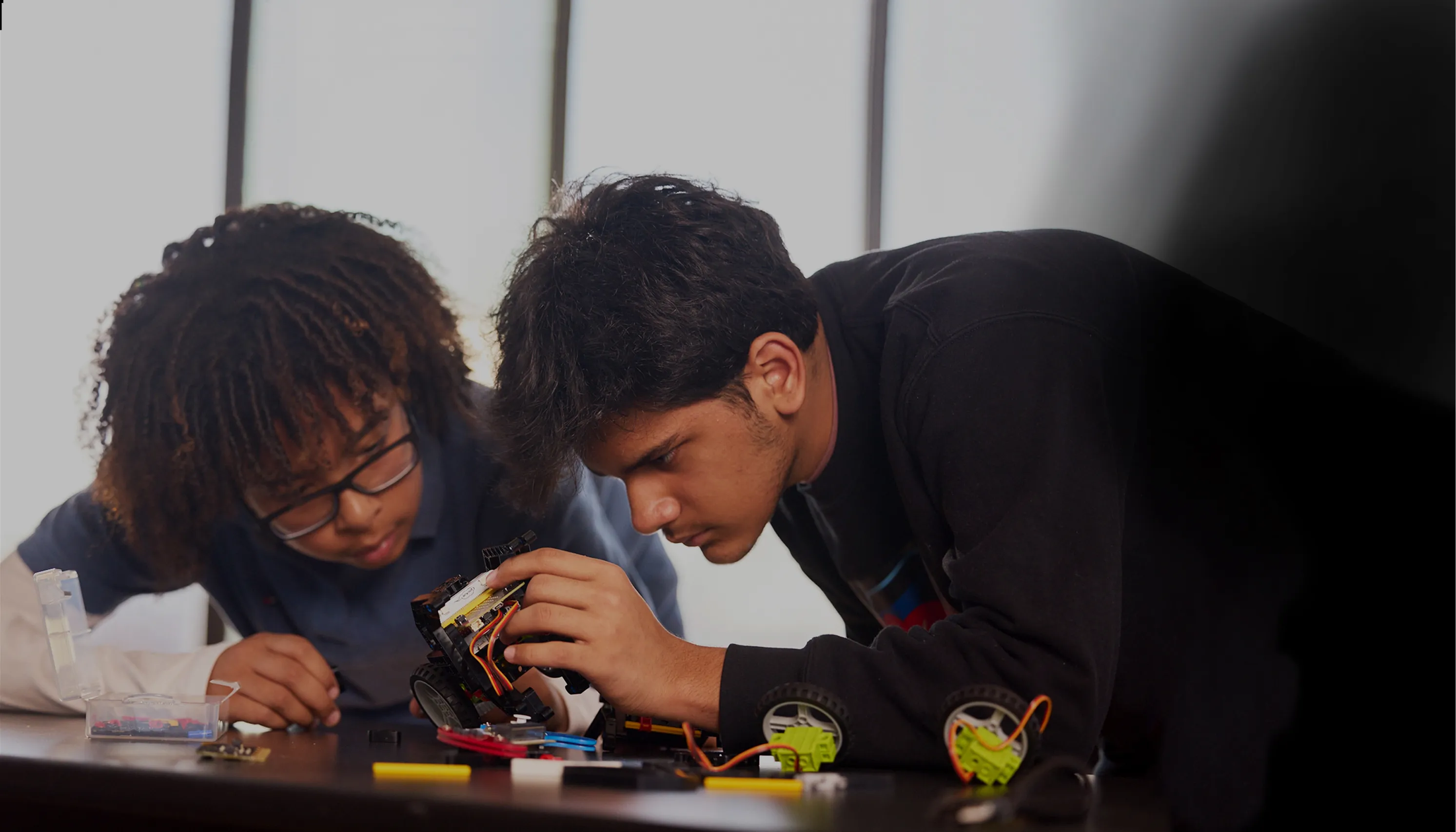 Two students looking closely at a robotic part