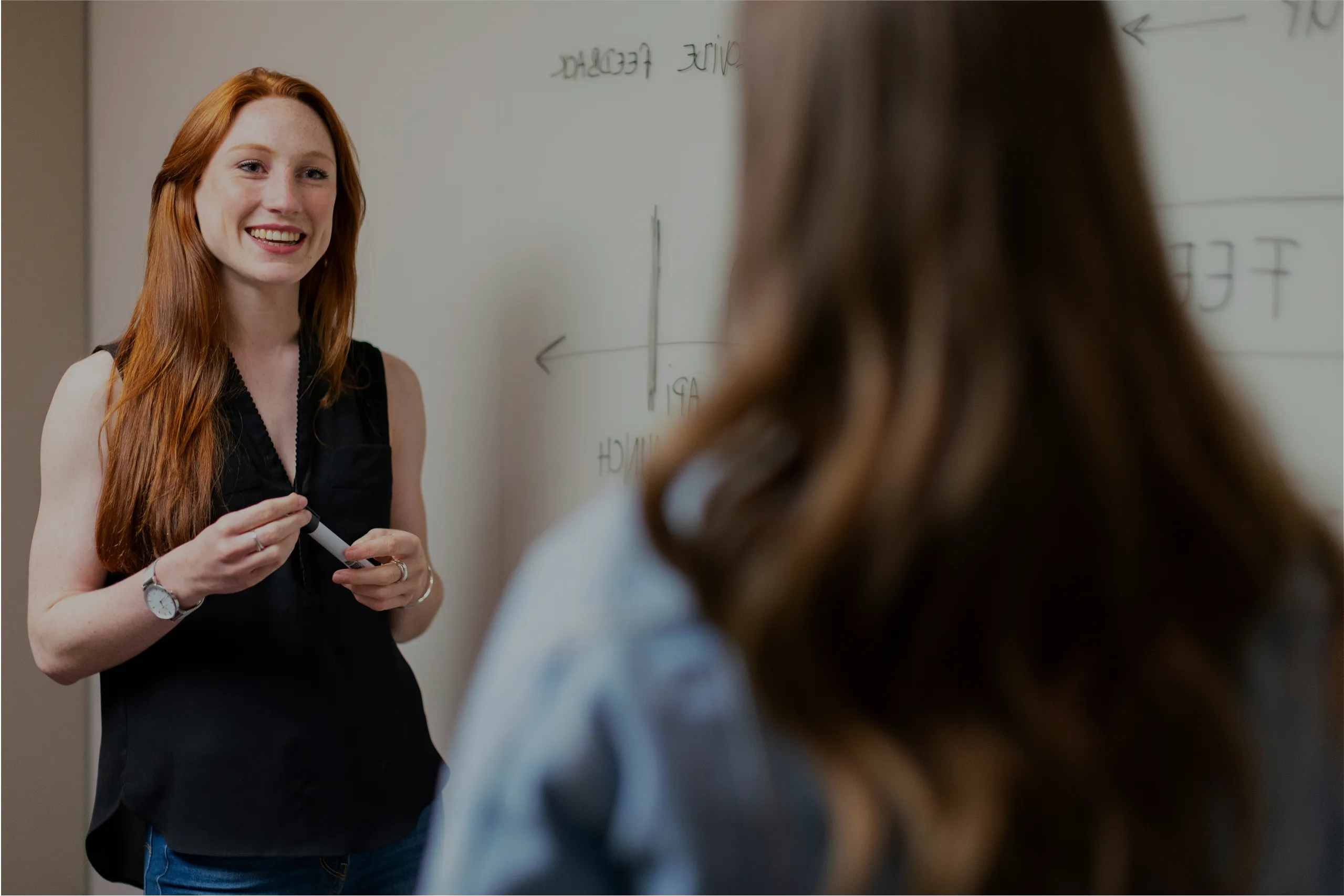 A teacher talking with a student next to a whiteboard.