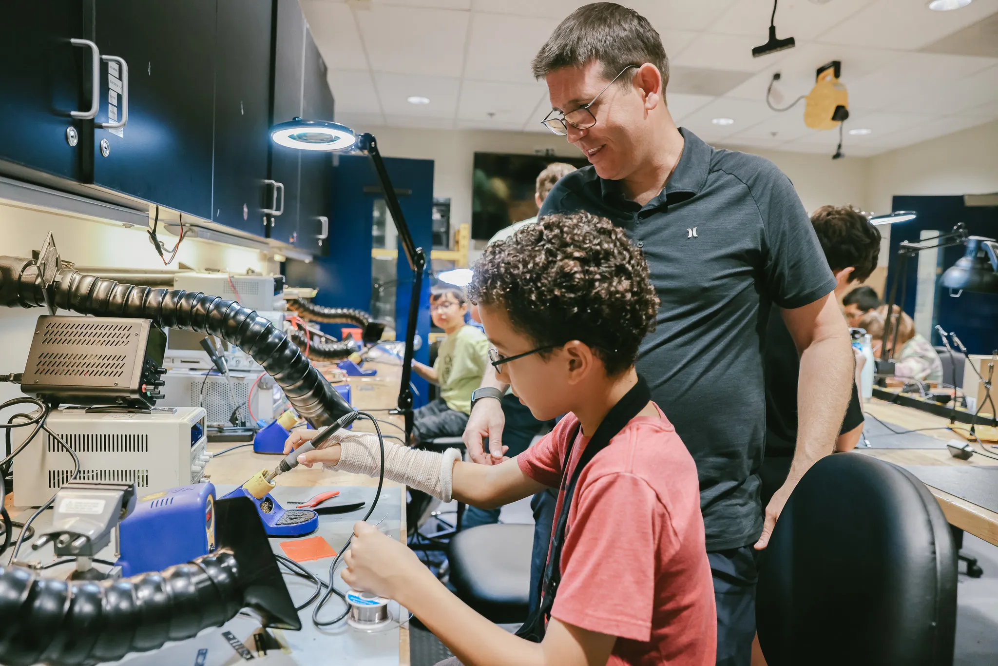 Teacher and student using a solder to build a robot