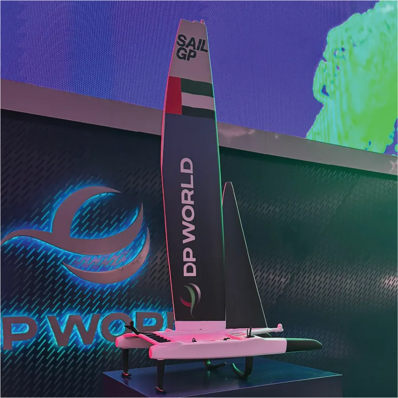 Model sailboat with DP World branding and UAE flag on the sail displayed indoors.