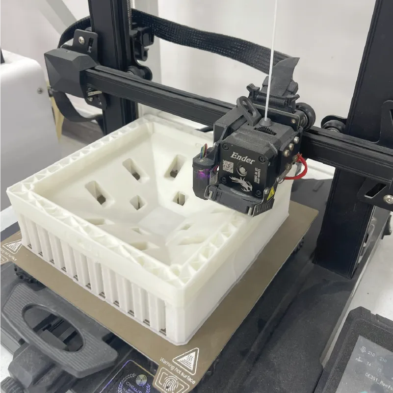 Ender 3D printer creating a white hollow square object with geometric patterns on the bed.