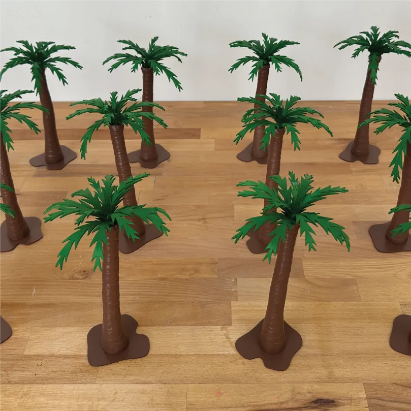 Several small plastic palm tree models arranged on a wooden surface.