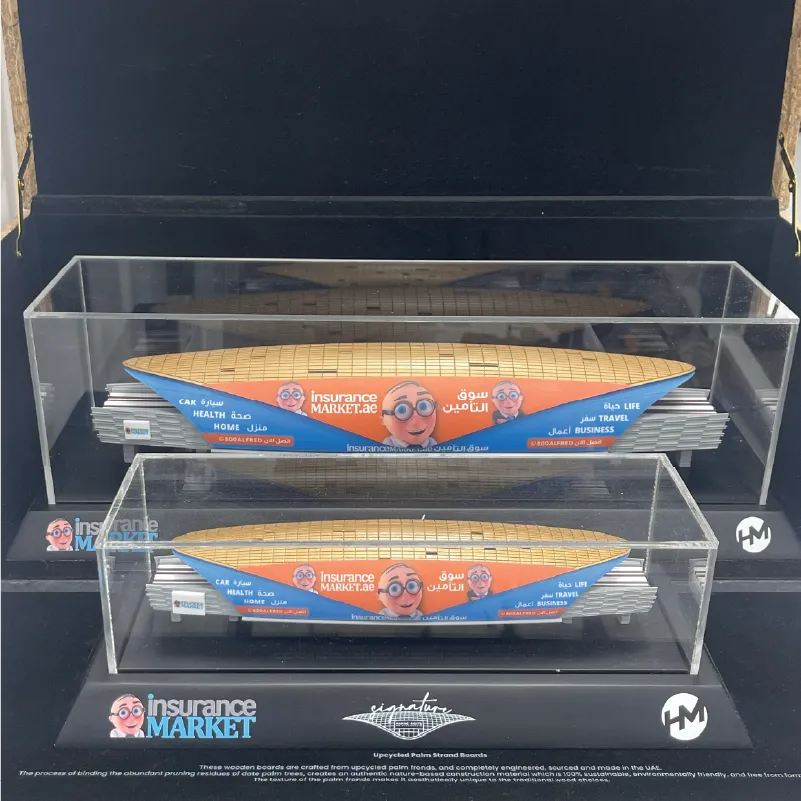 Two scale wooden models in clear cases with insuranceMARKET.ae branding on black display base.