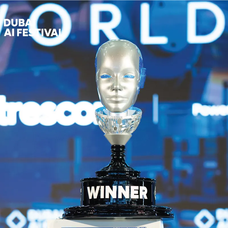 Trophy with a robotic head and 'WINNER' text, displayed at Dubai AI Festival event.