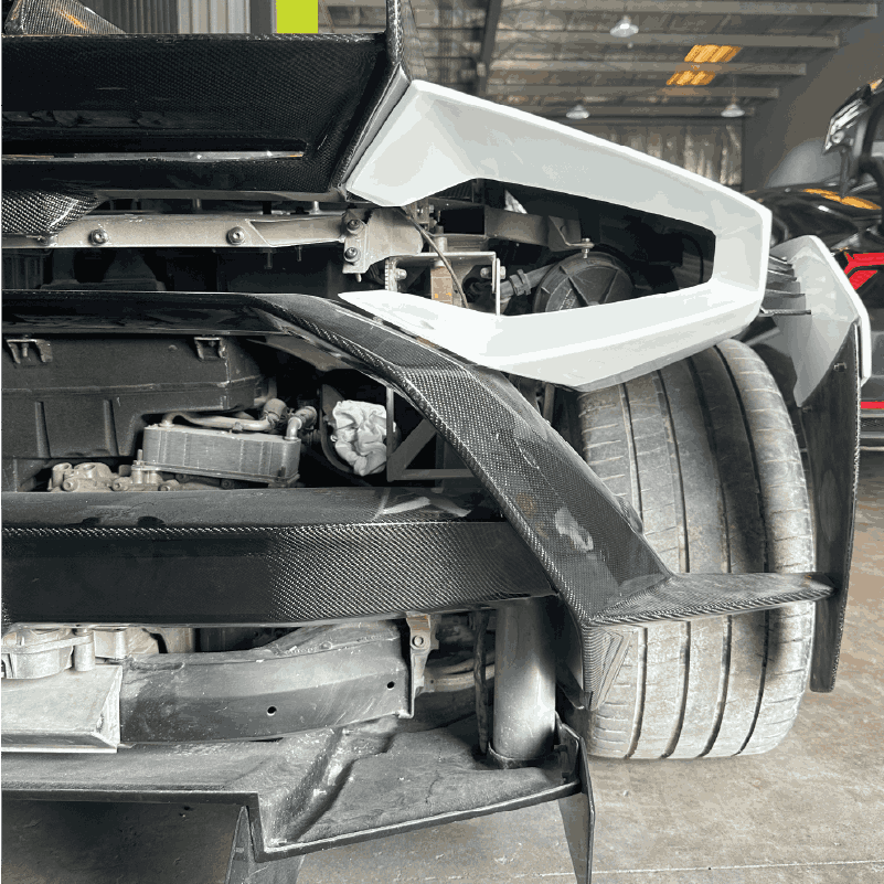 Close-up of the rear wheel and carbon fiber spoiler of a sports car in a garage.