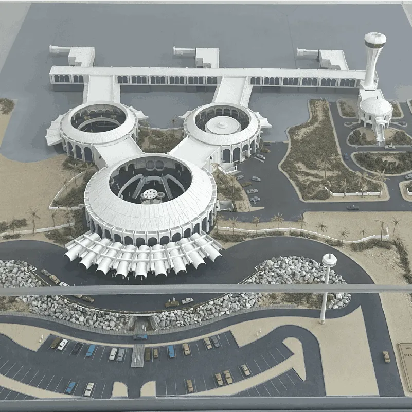 Scale model of a circular building complex with parking, roads, water, and landscaped areas.