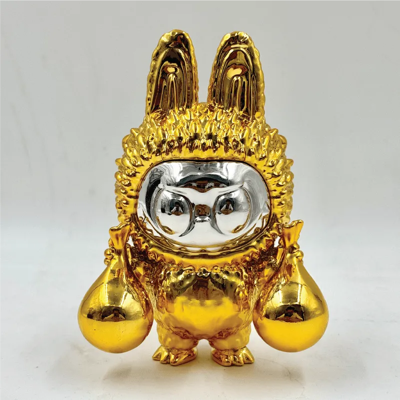 Gold and silver shiny figurine with rabbit ears holding two large droplets.