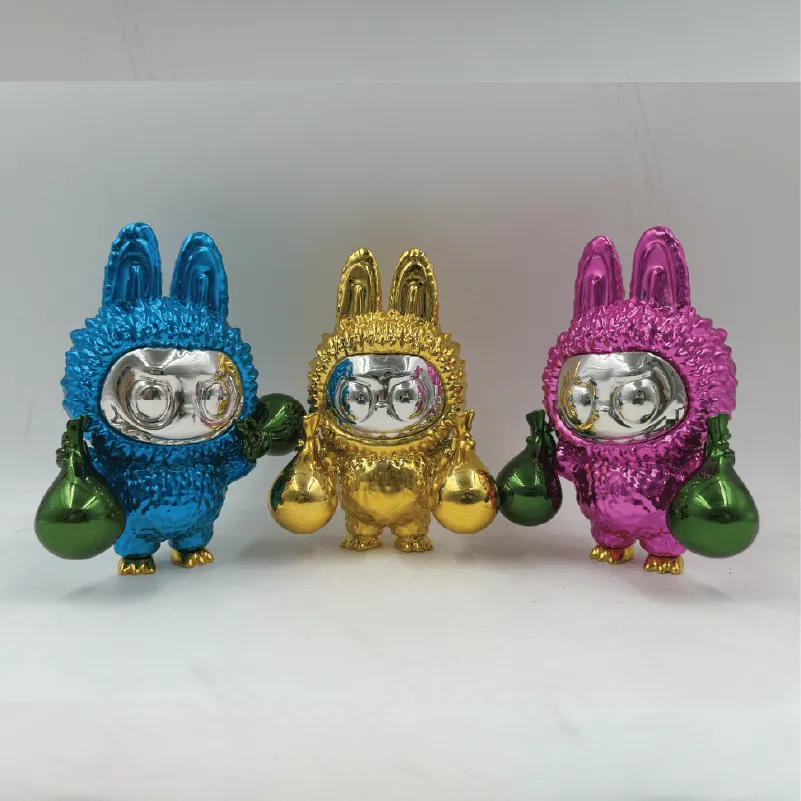 Three shiny bunny figurines in blue, gold, and pink, each holding two green or gold bags.