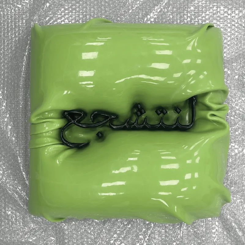 Glossy lime green square cake with Arabic text in black icing on crinkled plastic wrap.
