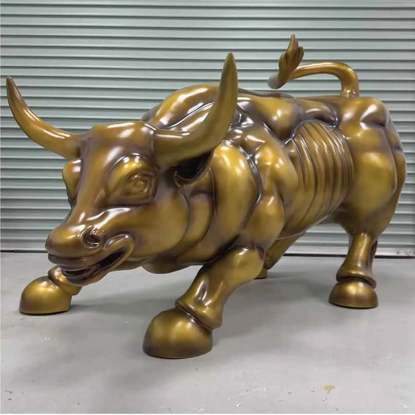 Shiny bronze bull sculpture with muscular form and horns, standing on a gray floor.