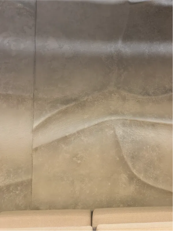 Abstract textured wall art with smooth wave-like patterns above beige cushioned seats.