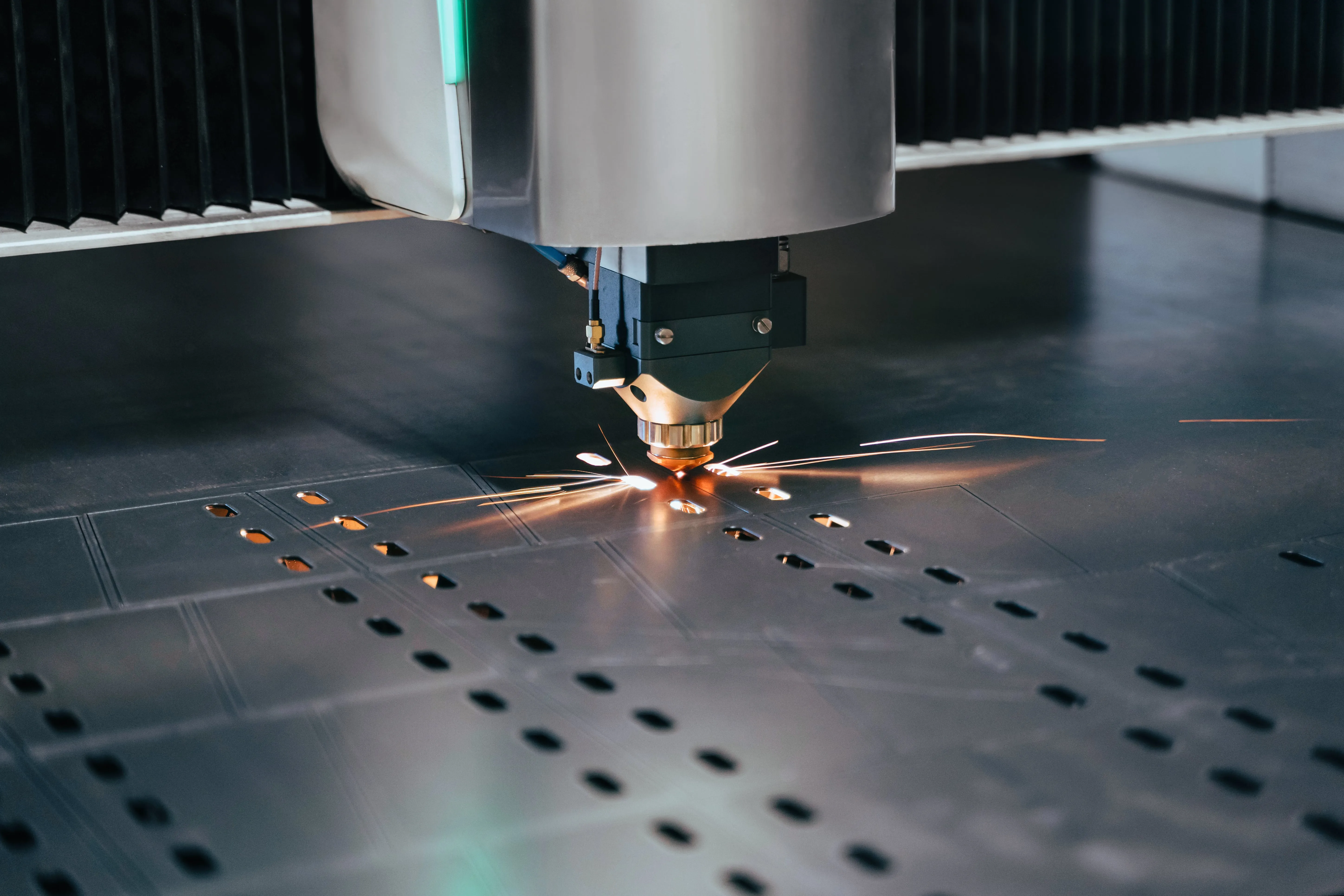 Close-up of a CNC laser cutting machine cutting metal sheet with sparks flying.
