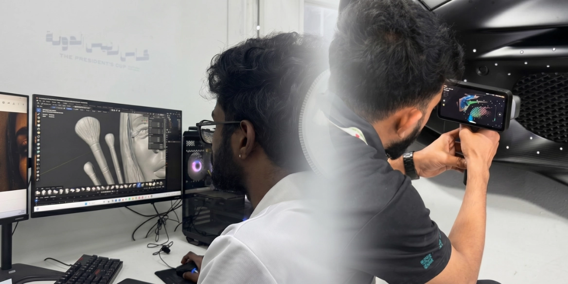 Man working on 3D modeling on a computer and scanning objects with a handheld device.