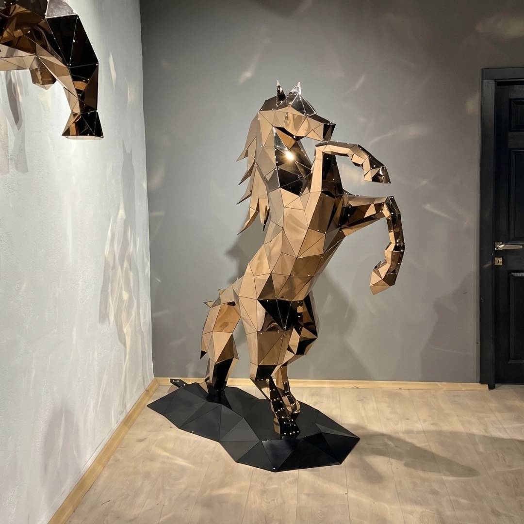 Geometric mirrored sculpture of a rearing horse standing on a black polygonal base in a room.