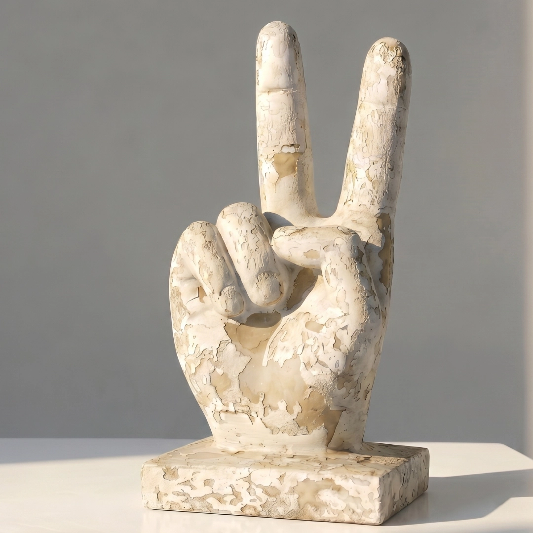 A weathered stone sculpture of a hand showing the peace sign on a flat base.