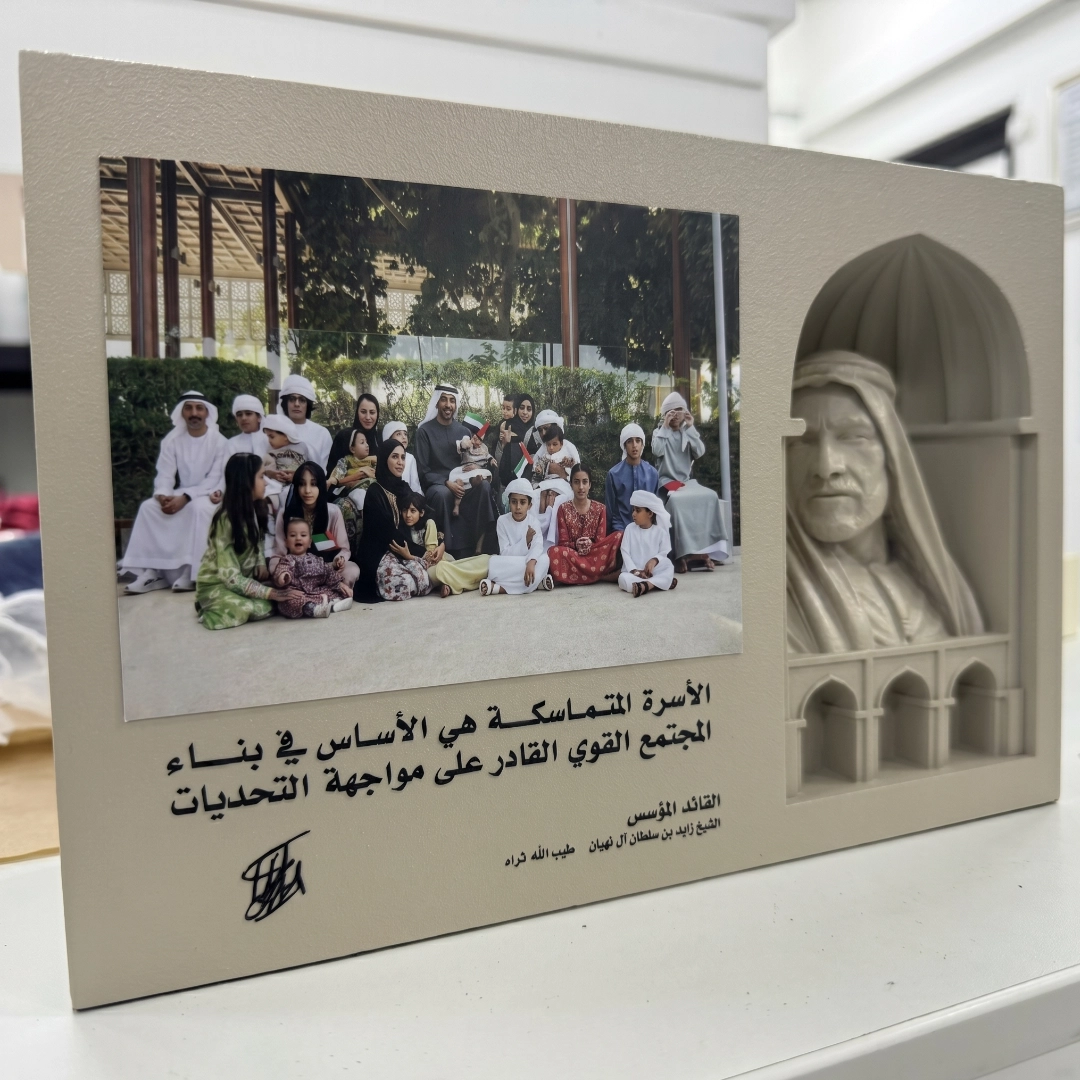 Plaque with a family photo, Arabic quote, and sculpted bust of a man in traditional Middle Eastern attire.