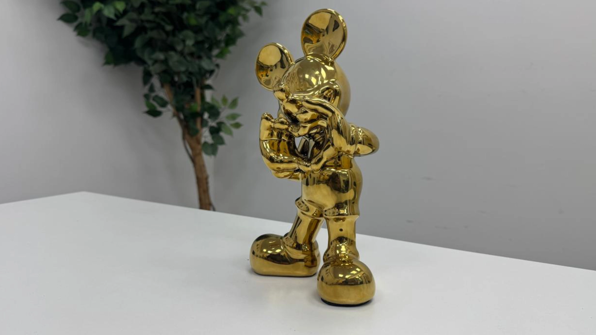 Stylised character sculpture in a mirror-gold finish.