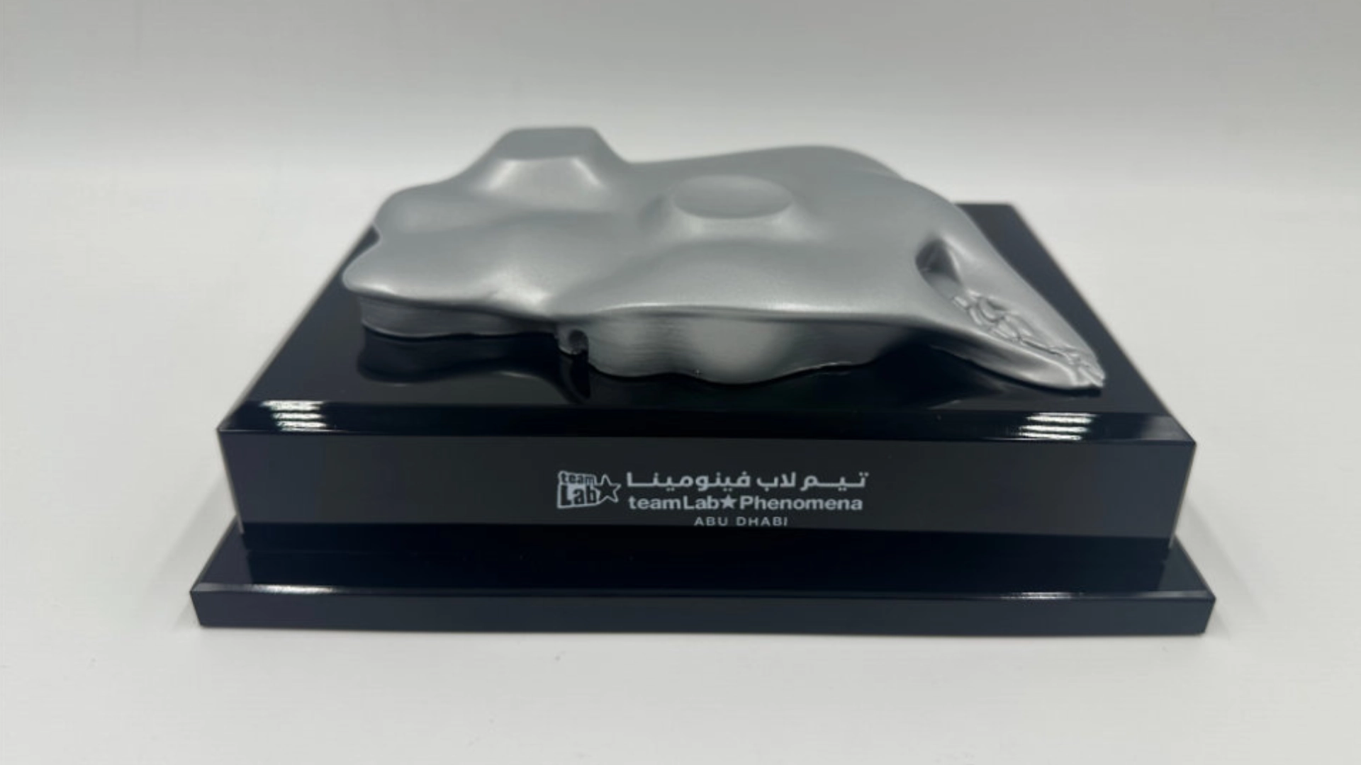 Silver abstract architectural sculpture displayed on a black base