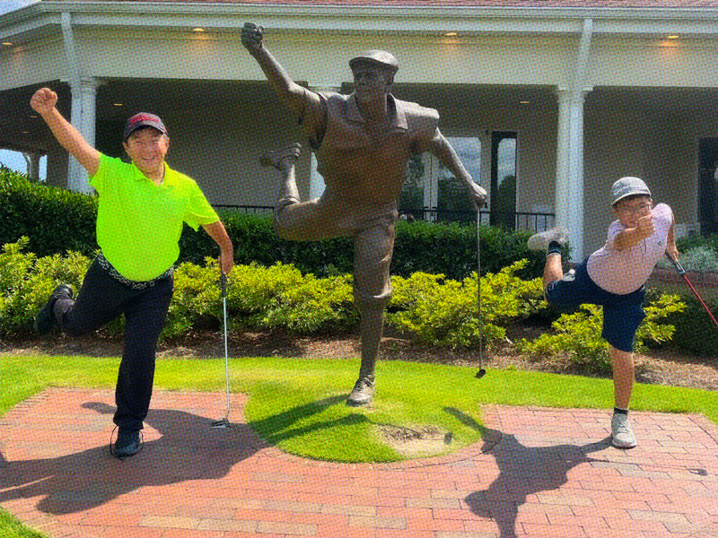 Two students posing next to the Payne Stewart statue at Pinehurst