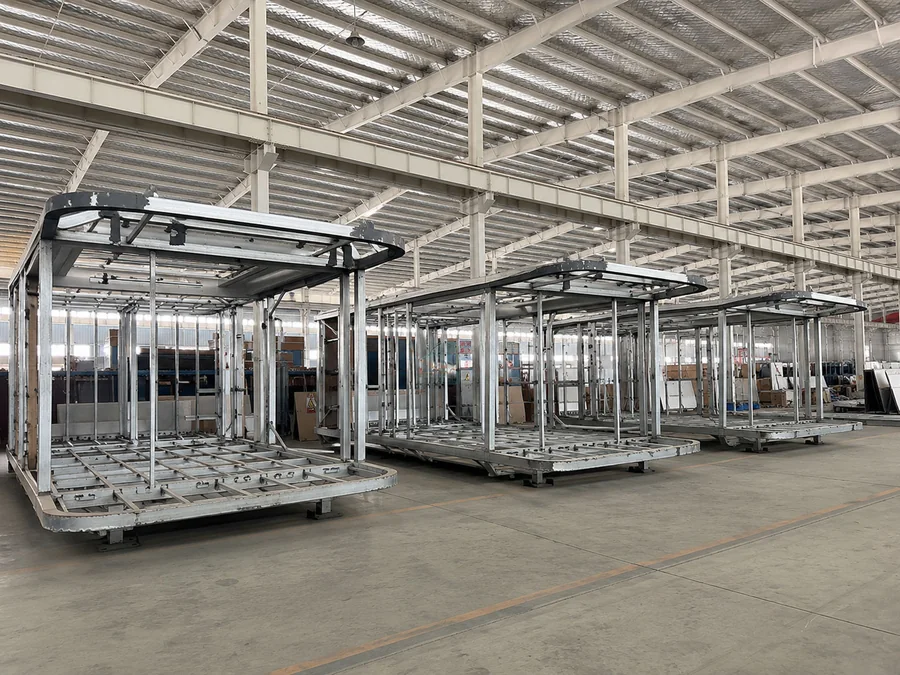 Bare steel capsule frames lined up on assembly carts inside the factory