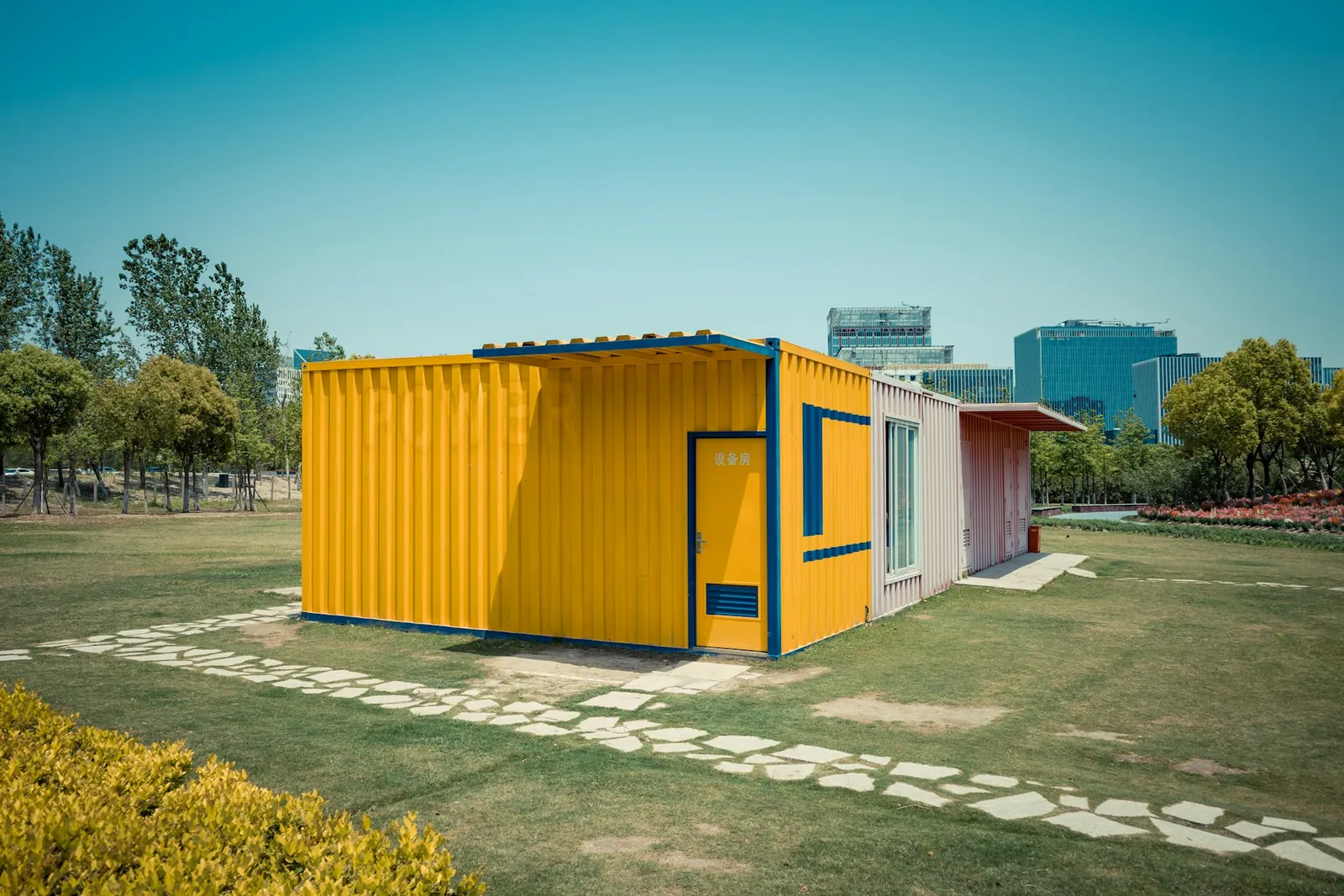 A small house made from a yellow shipping container on a lawn