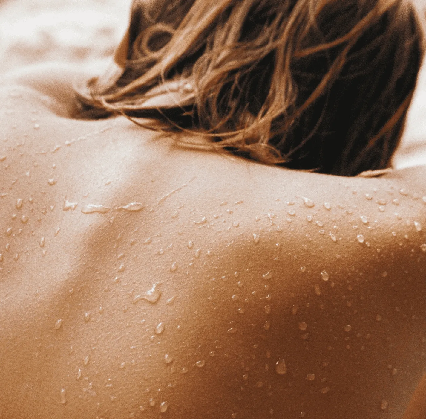 Wet hair and skin with water droplets, close-up sepia-toned view