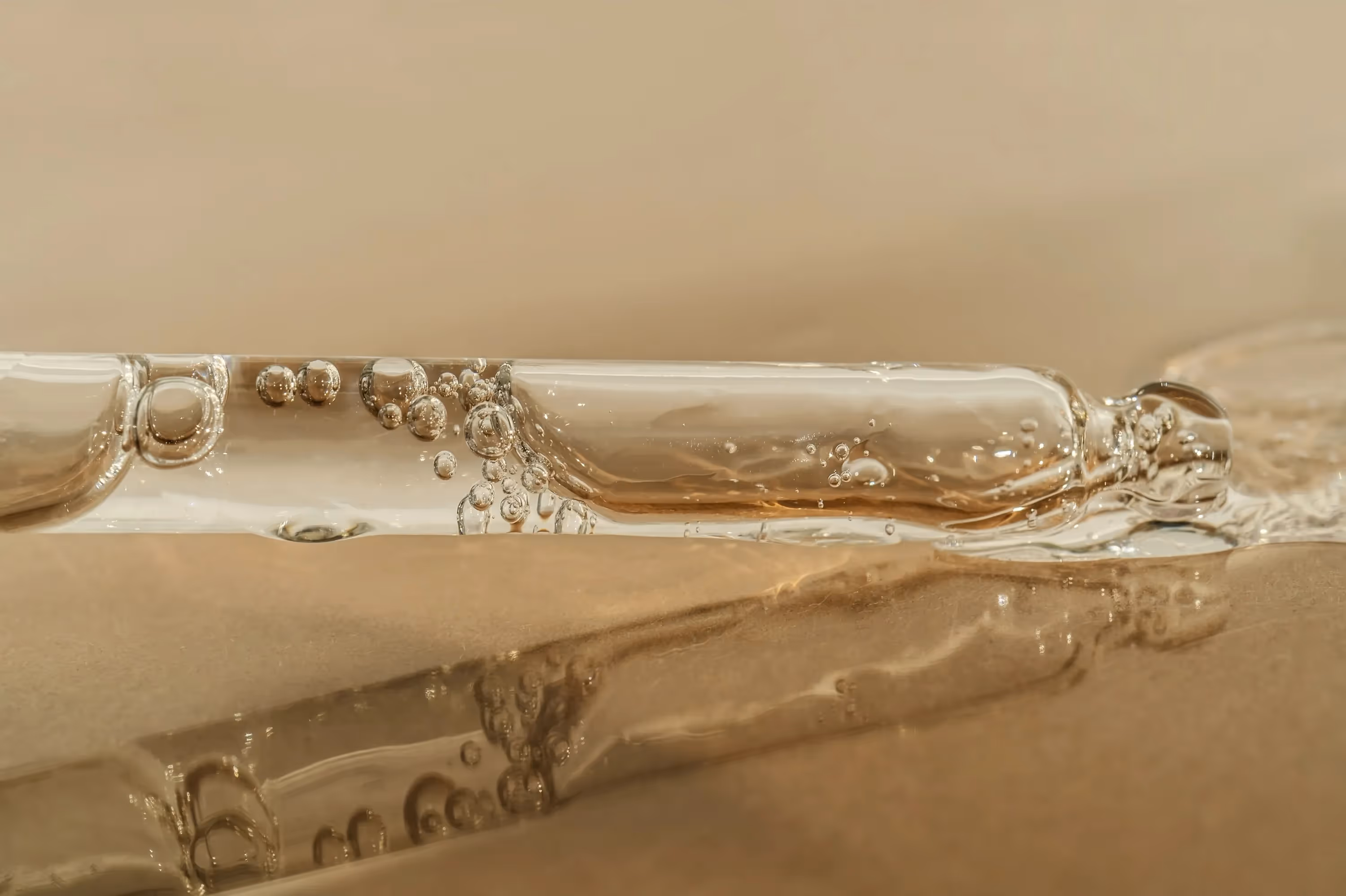 Transparent glass pipette with bubbles and serum liquid, creating flowing abstract shapes