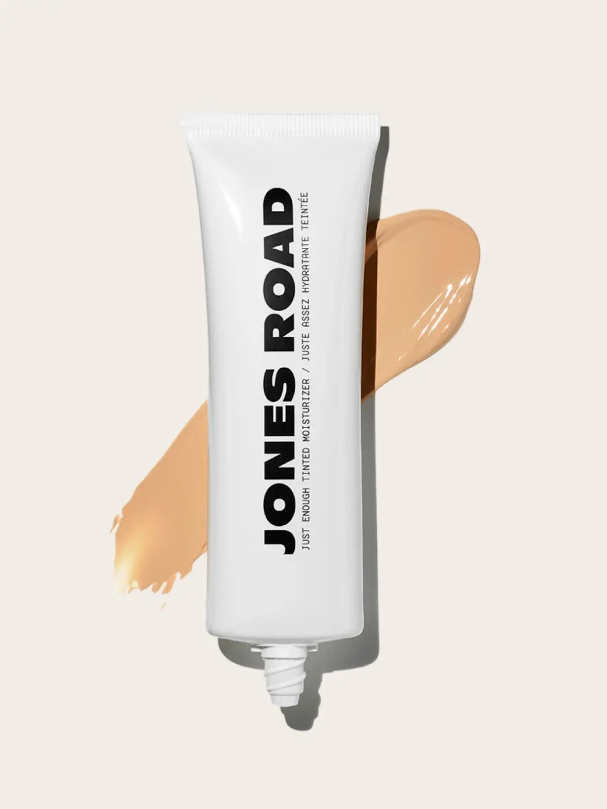 Jones Road tinted moisturizer tube with makeup swatch on light background