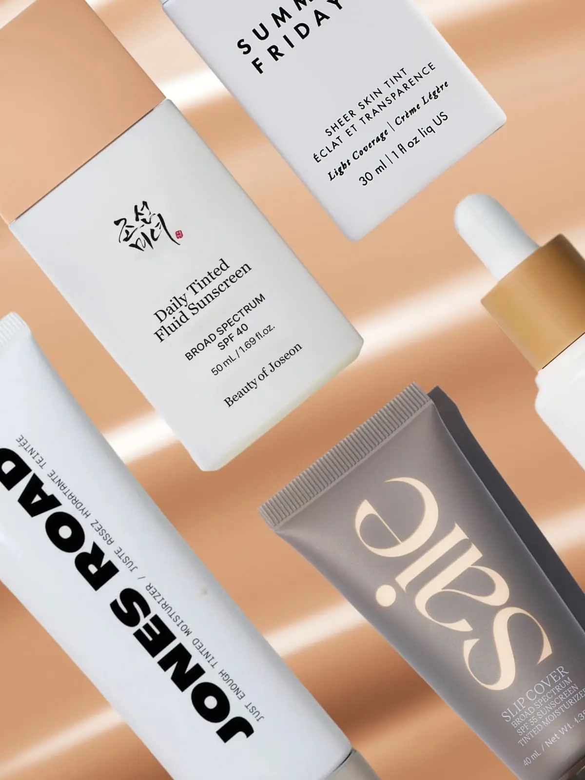 Tinted moisturiser products arranged on a soft peach background