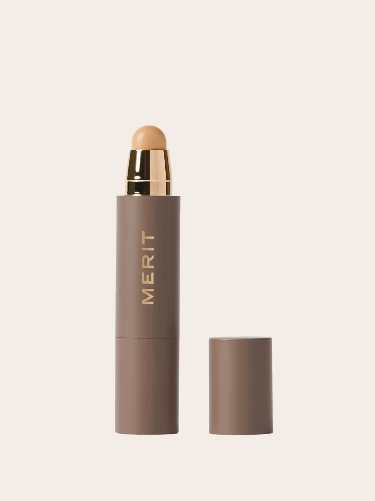 Merit makeup stick in brown tube with gold cap, cosmetic product