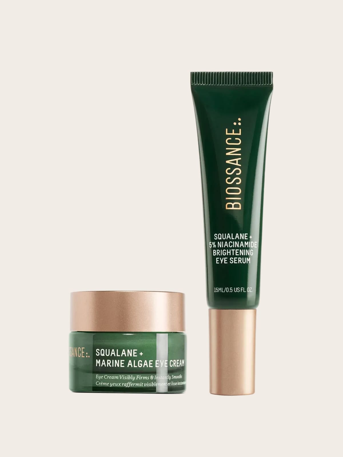 Biossance skincare set: green eye cream jar and brightening eye serum tube with gold accents