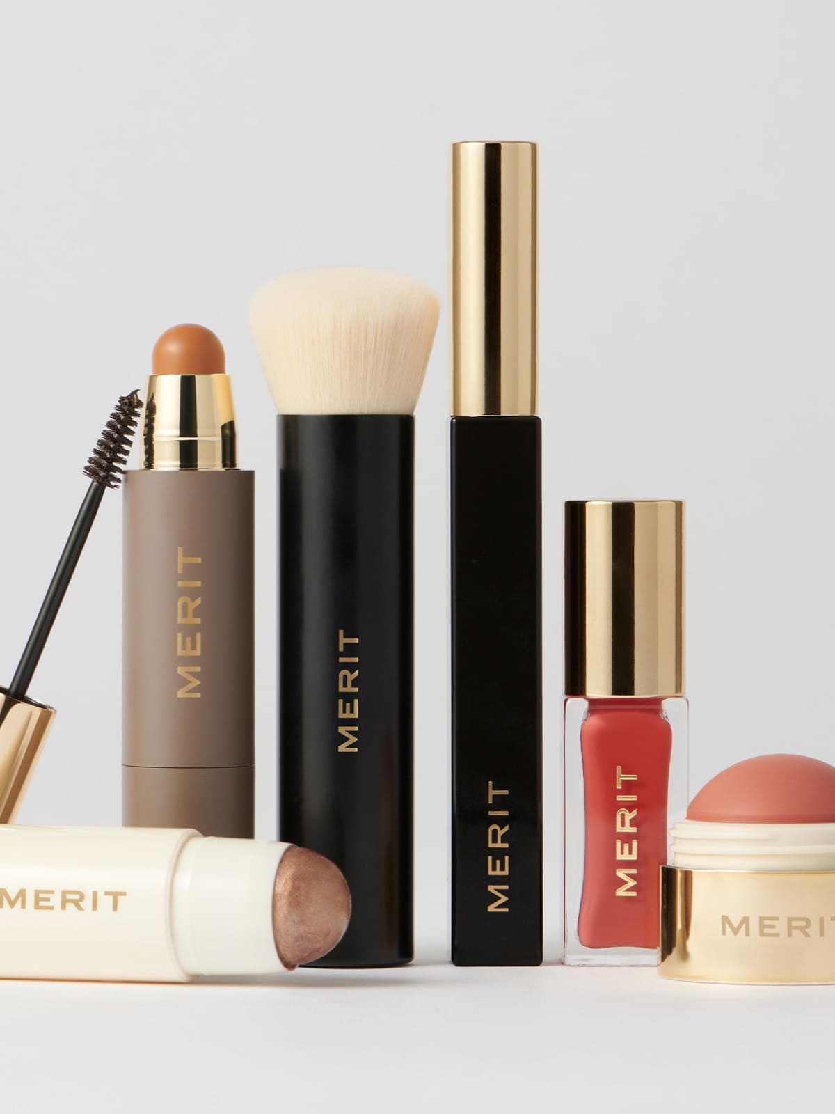 Collection of Merit brand cosmetics including mascara, brush, nail polish, and lipstick products