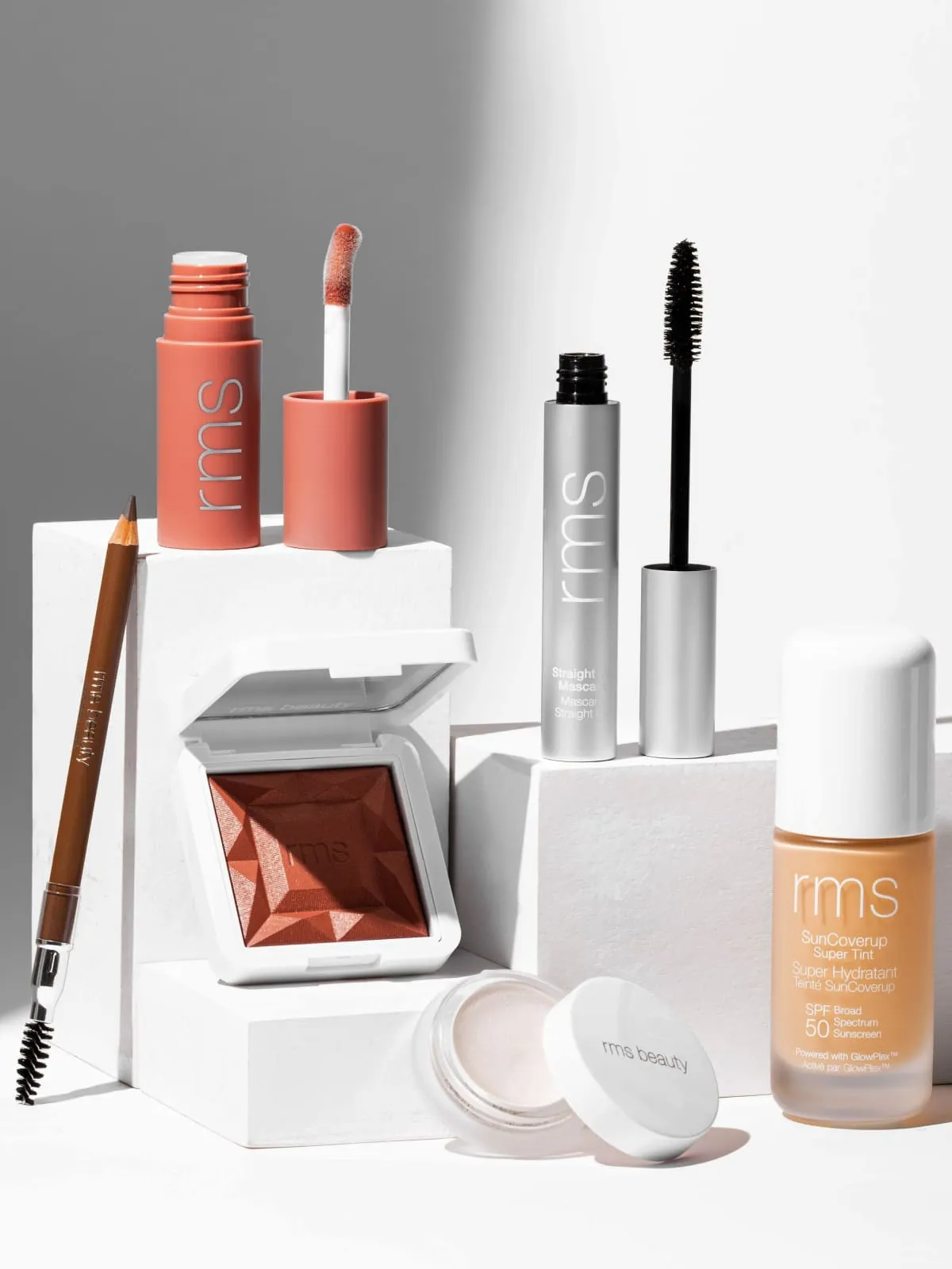 Collection of RMS Beauty cosmetics including mascara, lip tint, eyeshadow, and SPF sunscreen products.
