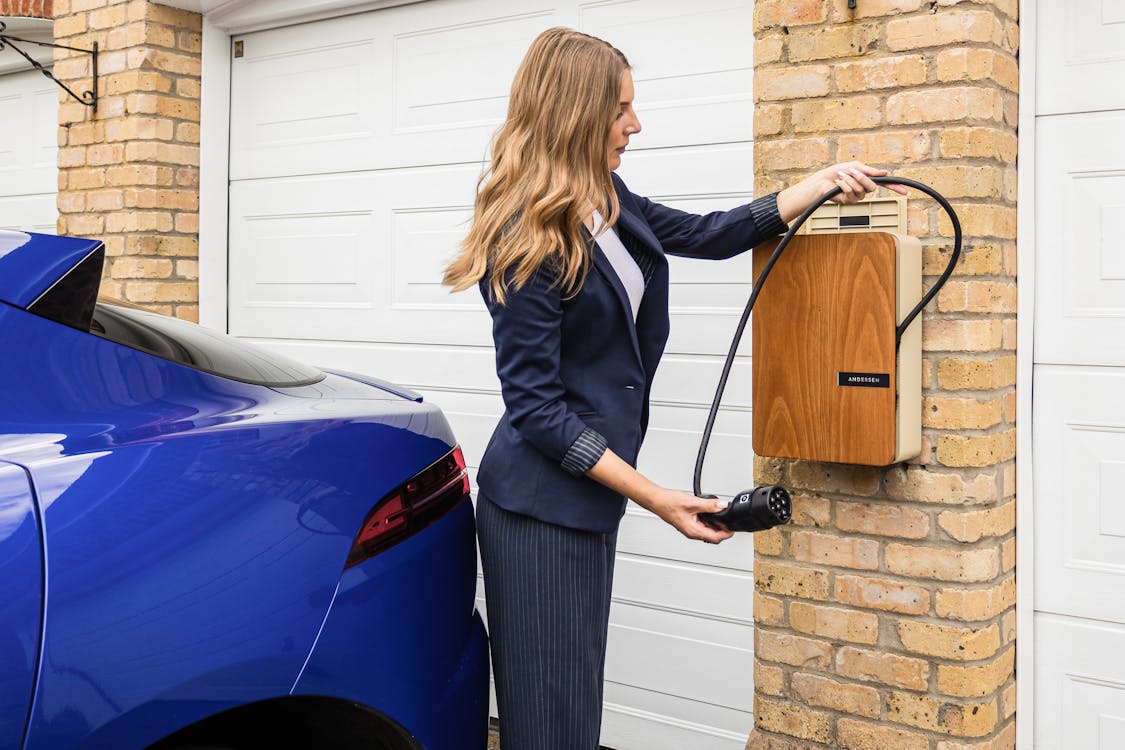 Woman plugging in EV charger at home in driveway - home EV charging installation