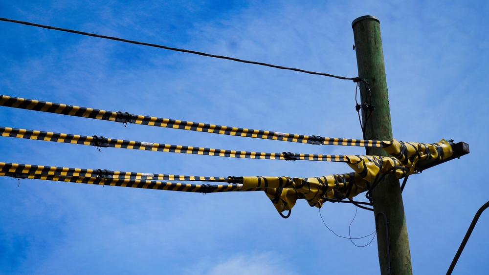 Level 2 electrician inspecting overhead service lines with tiger tail covers installed on live power cables in Sydney
