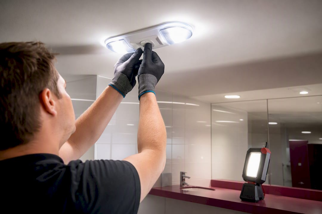 Hands pressing test button on emergency ceiling light