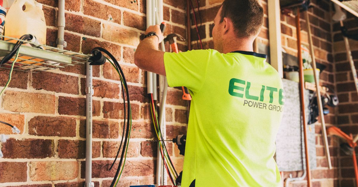 Electrician performing solar battery installation for sustainable energy storage in a home setting.