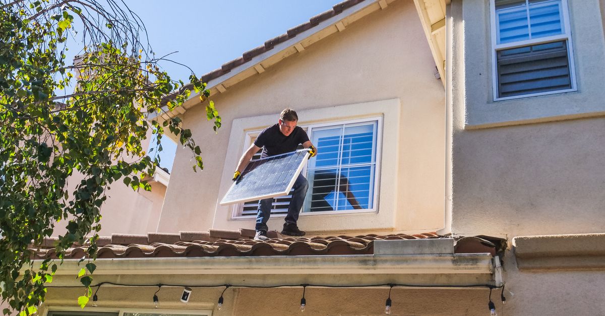 A solar technician installing panels on a house roof, emphasizing renewable energy.