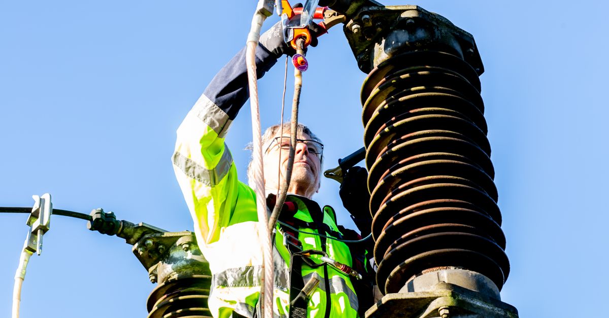 Safety-conscious worker inspecting high-voltage power structures on a clear day.