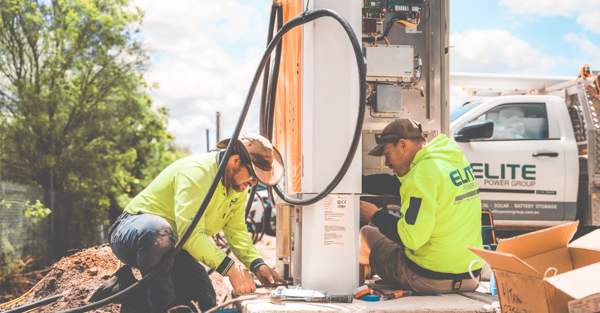 Two electricians working on electrical equipment installation outdoors in Tomago, NSW, Australia.
