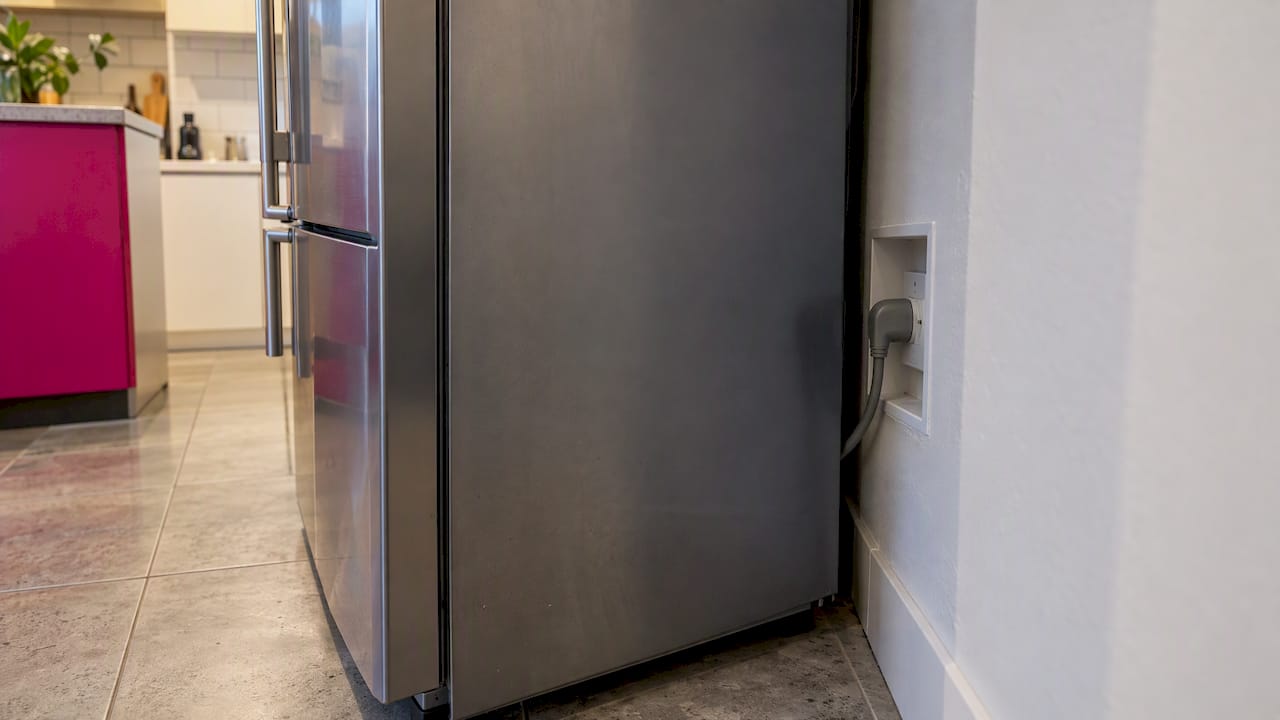 Recessed outlet behind a fridge in a kitchen
