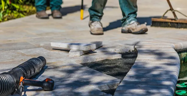 työntekijät asentavat laattoja pihatielle