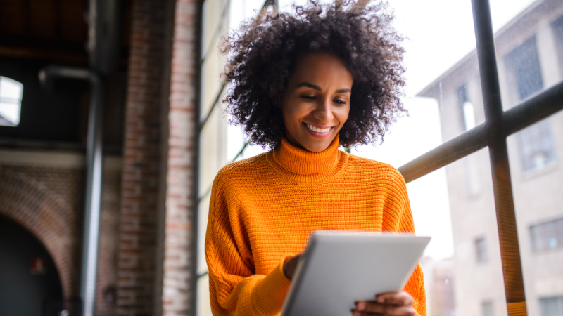 mixed woman in orange turtleneck on ipad