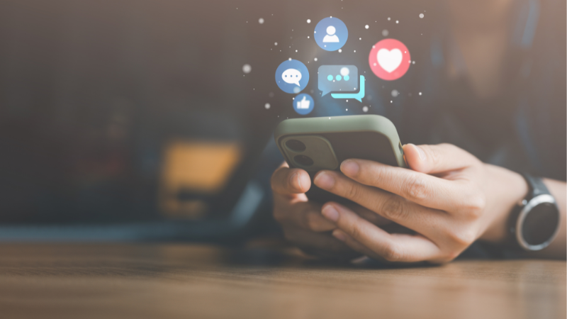 hands holding phone with social media icons above