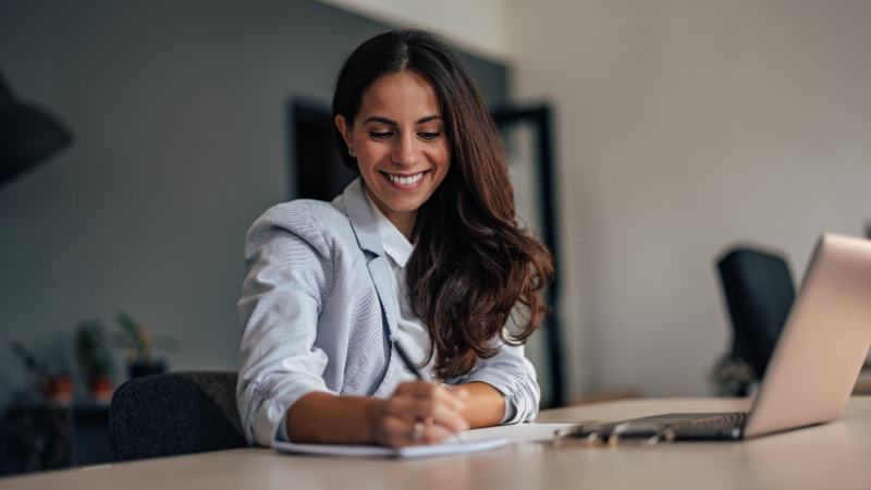 woman of color signing a contract in front of a laptop